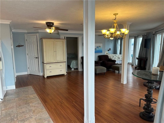 interior space featuring a textured ceiling, crown molding, baseboards, dark wood finished floors, and an inviting chandelier