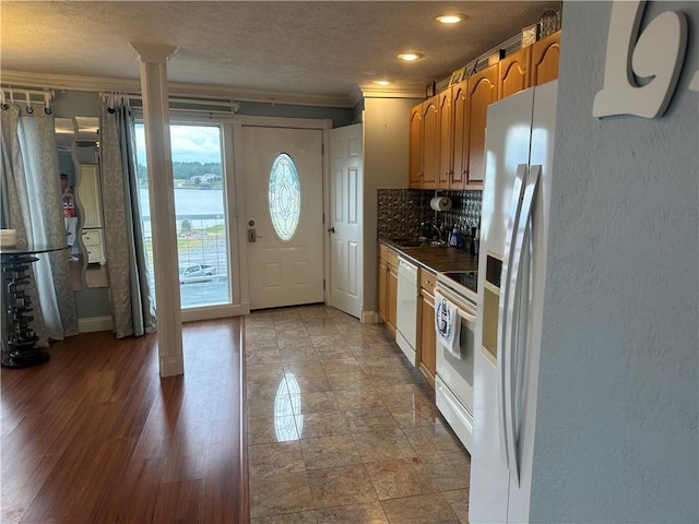 kitchen with white appliances, tasteful backsplash, a textured wall, dark countertops, and ornamental molding