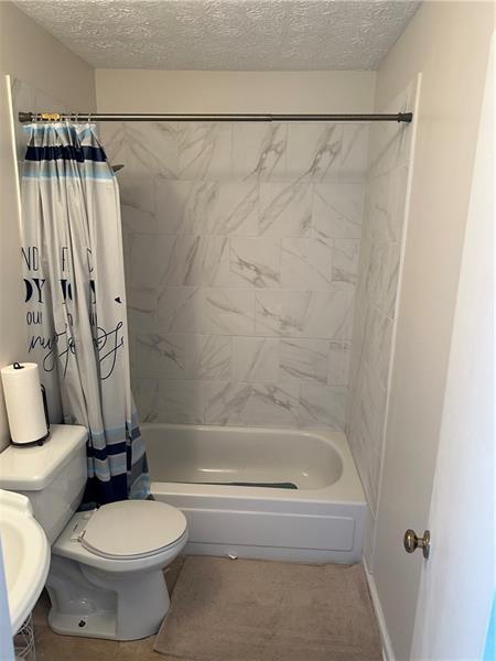 102 Cedar Chase Rd, Atlanta, GA 30324 - bathroom with tile patterned flooring, shower / bathtub combination with curtain, a textured ceiling, and toilet