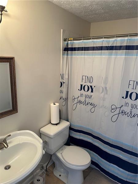 102 Cedar Chase Rd, Atlanta, GA 30324 - bathroom with tile patterned floors, sink, toilet, a textured ceiling, and curtained shower