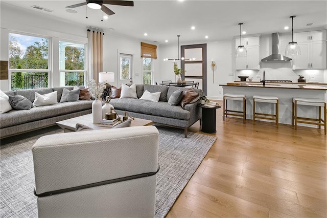 living room featuring ceiling fan, light wood-type flooring, and sink