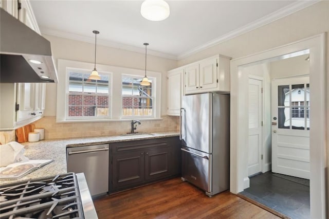 kitchen featuring appliances with stainless steel finishes, a sink, range hood, light stone counters, and dark wood finished floors