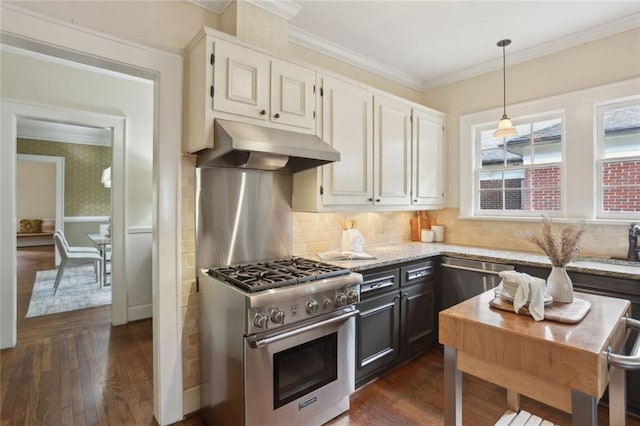 kitchen with appliances with stainless steel finishes, under cabinet range hood, ornamental molding, light stone counters, and dark wood-style flooring