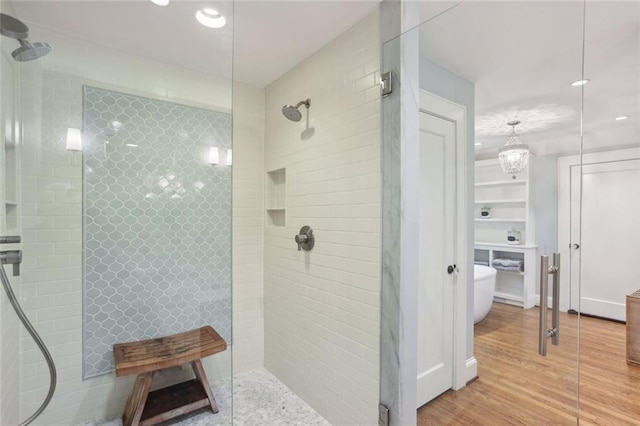 bathroom with tiled shower, recessed lighting, and wood finished floors