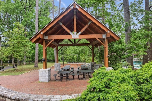 view of community featuring a gazebo, a patio, and view of wooded area
