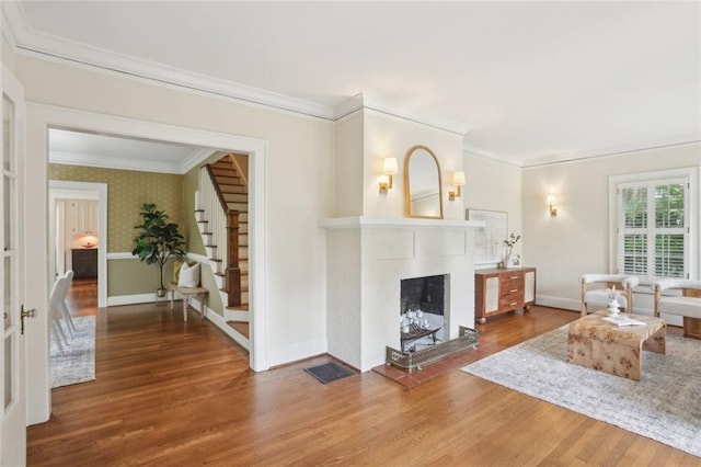 living room featuring wood finished floors, crown molding, baseboards, stairway, and a fireplace