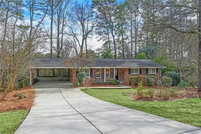 ranch-style house featuring a carport, driveway, a front lawn, and brick siding