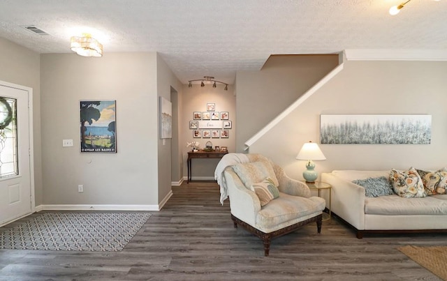 living room featuring a textured ceiling, visible vents, wood finished floors, and baseboards