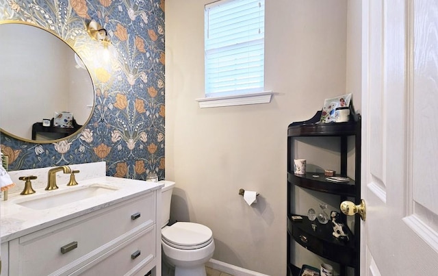 bathroom featuring baseboards, wallpapered walls, toilet, and vanity