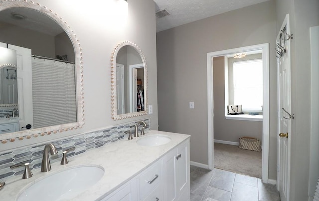 full bathroom featuring baseboards, visible vents, double vanity, and a sink