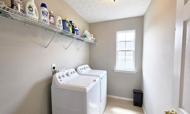 laundry area featuring light tile patterned floors, washing machine and dryer, laundry area, baseboards, and a textured ceiling