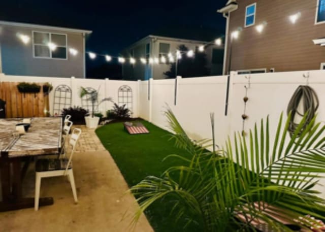 yard at night with a patio, fence, and outdoor dining area