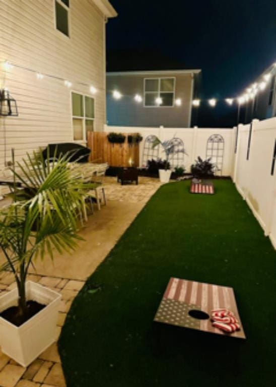 yard at night featuring a fenced backyard and a patio area