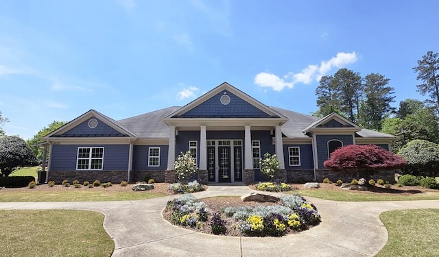 exterior space with a front yard, french doors, and stone siding