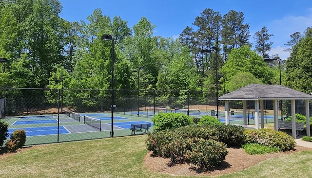 view of tennis court featuring a yard and fence