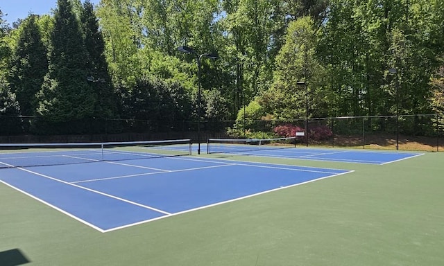 view of tennis court with community basketball court and fence