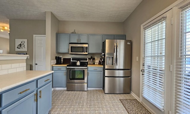 kitchen with a textured ceiling, stainless steel appliances, and light countertops