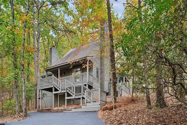 view of front facade with covered porch, stairway, and a chimney