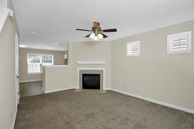 unfurnished living room featuring ceiling fan and dark colored carpet