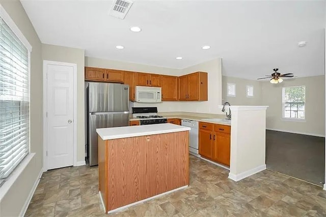 kitchen featuring sink, white appliances, ceiling fan, a center island, and kitchen peninsula