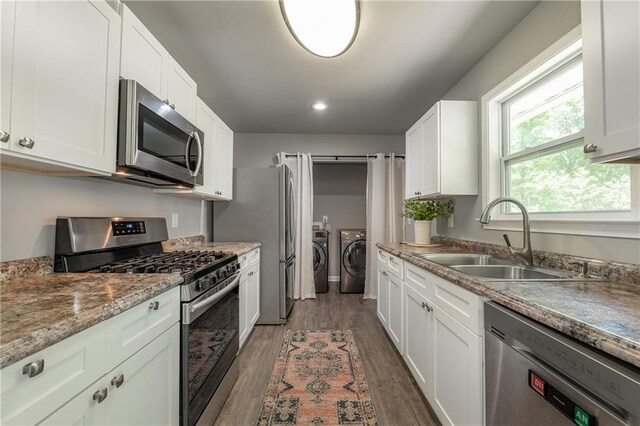 4408 Brandon Ct NE, Marietta, GA 30066 - kitchen with stainless steel appliances, washer and clothes dryer, a sink, dark wood-style flooring, and white cabinetry