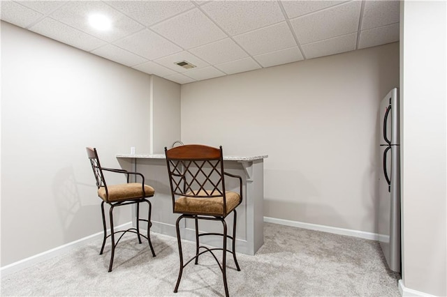 dining space featuring light carpet and a drop ceiling