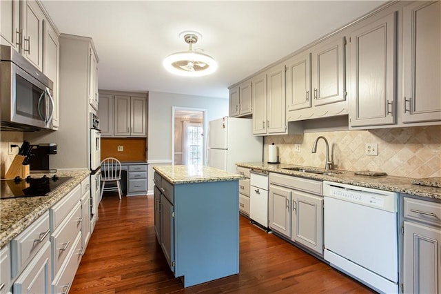 kitchen featuring white appliances, light stone countertops, sink, and a kitchen island