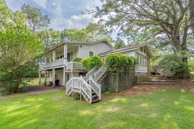 rear view of property with a wooden deck, a patio, and a lawn