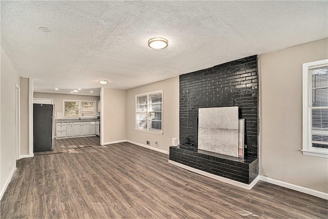 unfurnished living room featuring dark hardwood / wood-style floors, a fireplace, and a textured ceiling