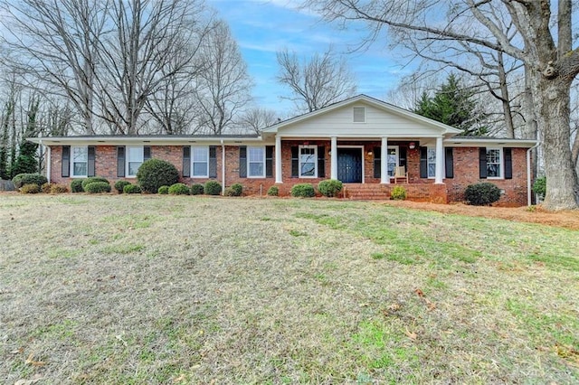 ranch-style house featuring covered porch and a front yard