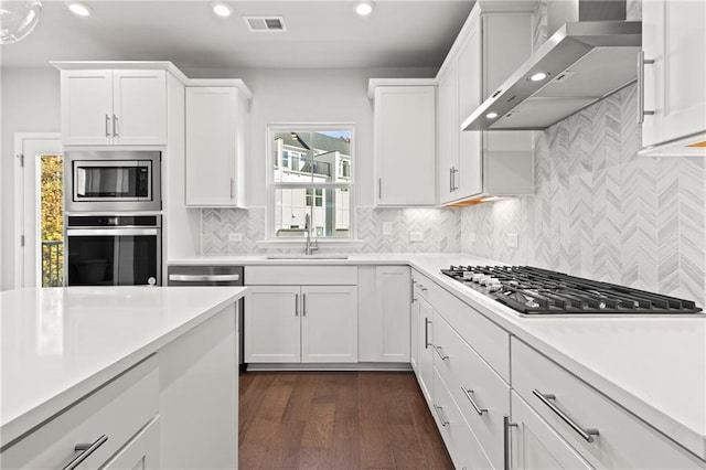 kitchen featuring white cabinets, wall chimney exhaust hood, stainless steel appliances, sink, and dark hardwood / wood-style floors