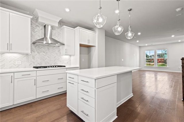 kitchen with pendant lighting, white cabinets, a center island, gas cooktop, and wall chimney range hood