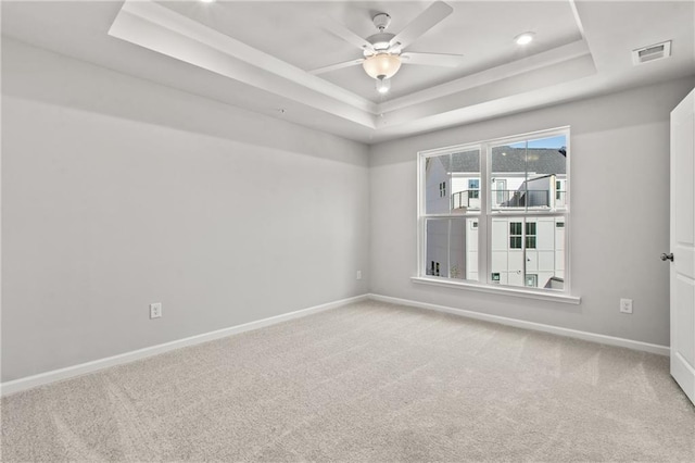 carpeted spare room with ceiling fan and a raised ceiling