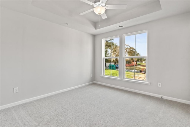 unfurnished room with ceiling fan, a raised ceiling, and carpet flooring