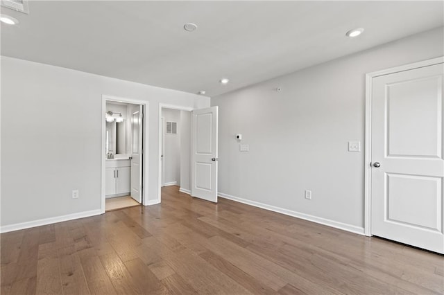 unfurnished bedroom with light hardwood / wood-style flooring and connected bathroom