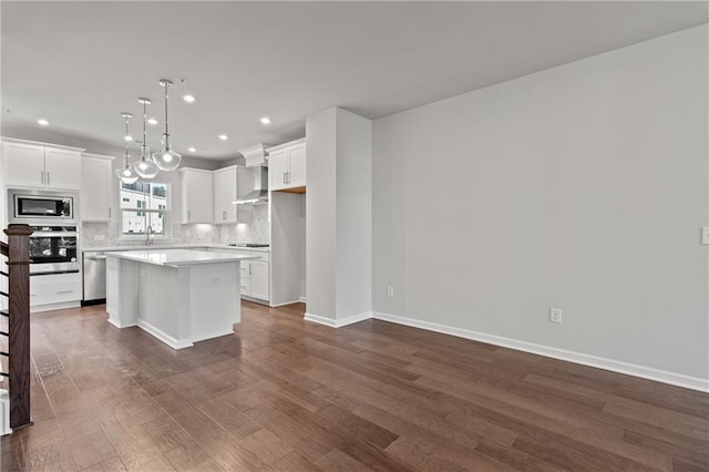 kitchen featuring white cabinets, a center island, wall chimney exhaust hood, decorative light fixtures, and stainless steel appliances