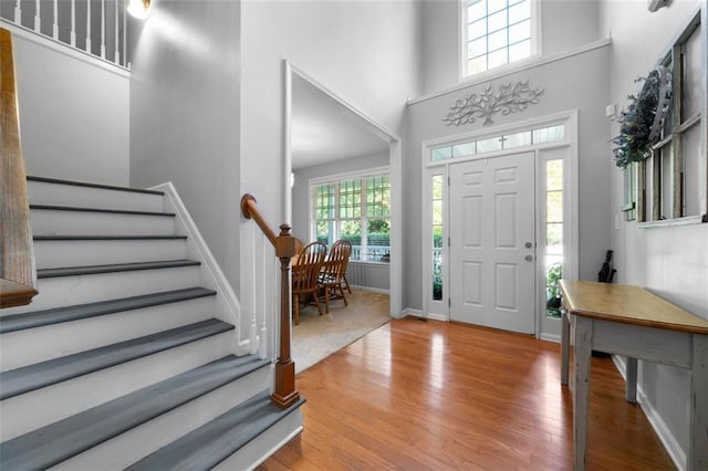 foyer entrance with a wealth of natural light, light hardwood / wood-style floors, and a high ceiling