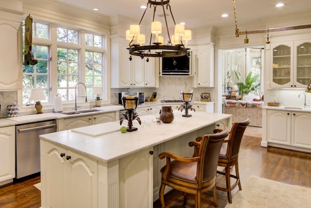 kitchen featuring decorative backsplash, stainless steel dishwasher, dark wood-type flooring, a kitchen island, and crown molding