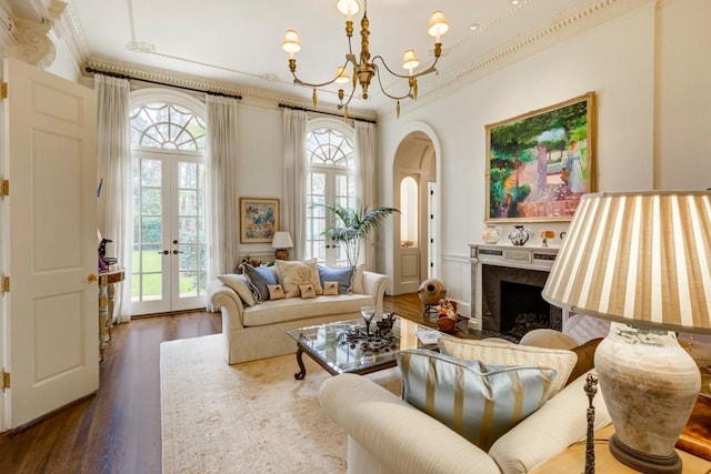 living room with dark hardwood / wood-style flooring, french doors, an inviting chandelier, crown molding, and a premium fireplace