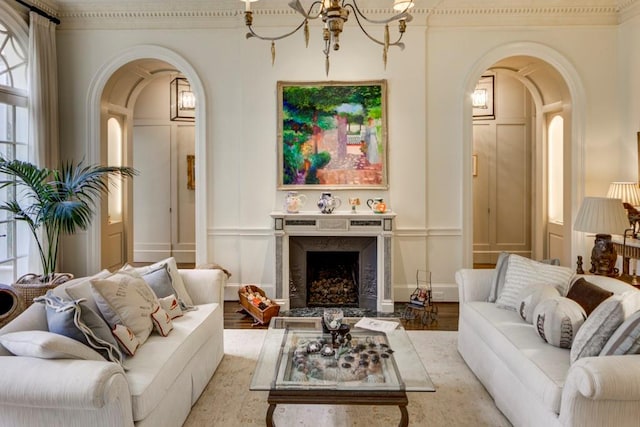 living room featuring hardwood / wood-style flooring, an inviting chandelier, a premium fireplace, and crown molding