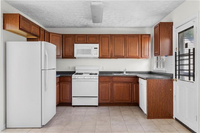 kitchen with a textured ceiling, sink, plenty of natural light, and white appliances