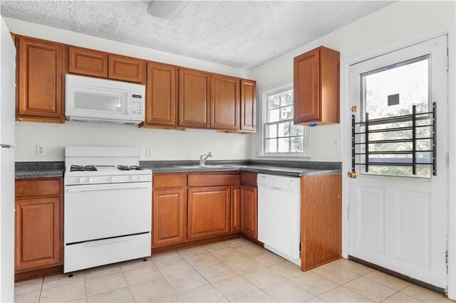 kitchen featuring white appliances, a textured ceiling, light tile patterned floors, and sink