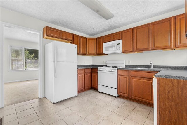 kitchen featuring white appliances, a textured ceiling, light tile patterned flooring, and sink