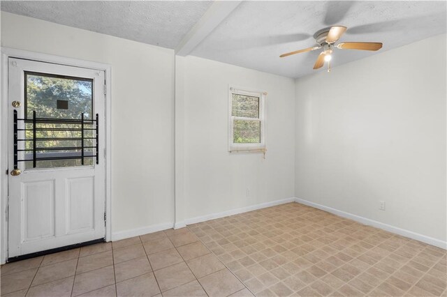 tiled spare room featuring ceiling fan, a textured ceiling, and a wealth of natural light