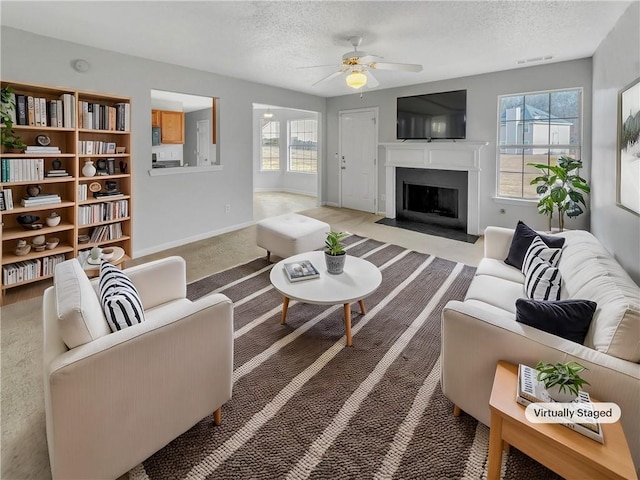 carpeted living room with ceiling fan and a textured ceiling