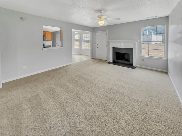 unfurnished living room featuring ceiling fan, light carpet, and a textured ceiling