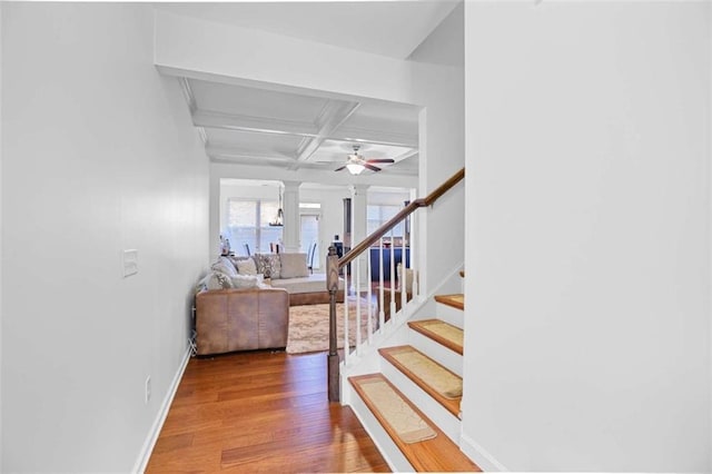 staircase with coffered ceiling, hardwood / wood-style floors, beamed ceiling, and ornate columns