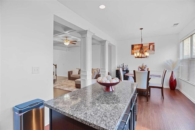 kitchen featuring dark hardwood / wood-style floors, ceiling fan with notable chandelier, decorative light fixtures, decorative columns, and a center island