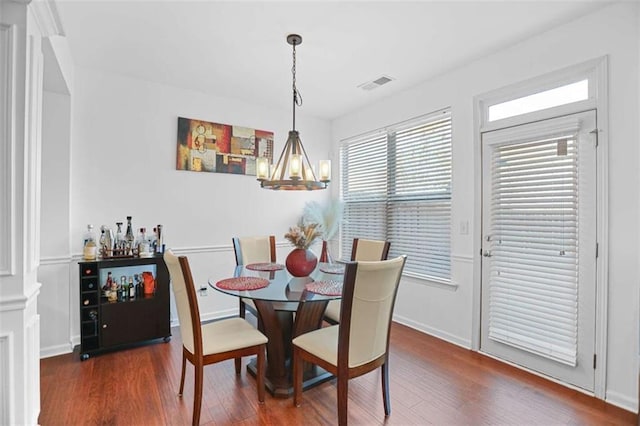 dining room with dark wood-type flooring and a notable chandelier