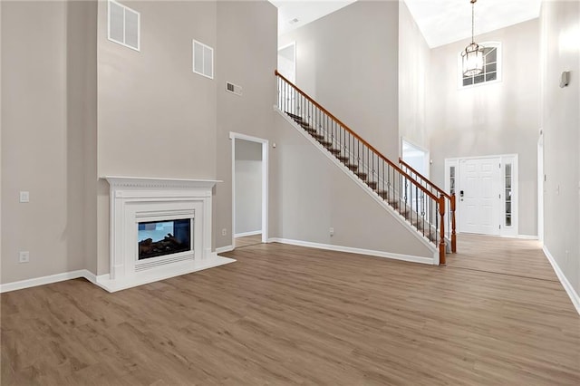 unfurnished living room with hardwood / wood-style floors and high vaulted ceiling